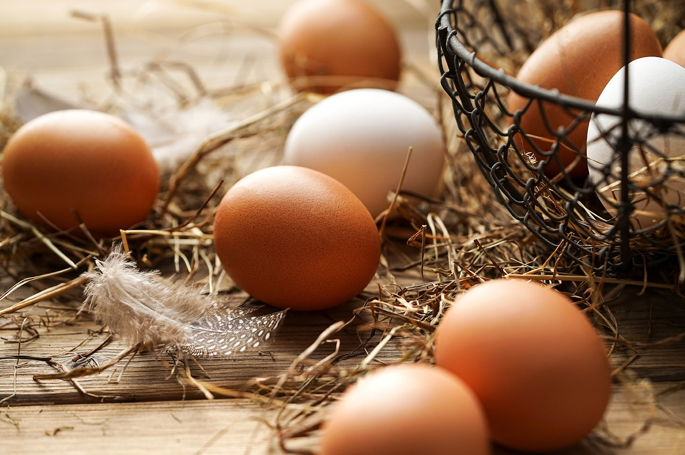 Some brown eggs sitting on table next to wire basket
