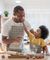 Young kid putting frosting on dad's nose in kitchen