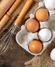 close up of brown and white eggs in a carton next to kitchen utensils