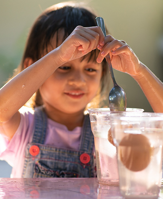 Young child stirring egg in plastic cup