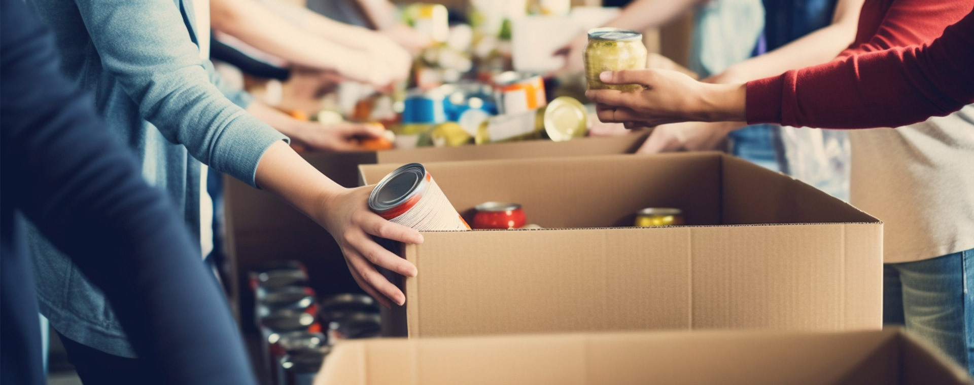 Volunteers filling up cardboard boxes of canned goods