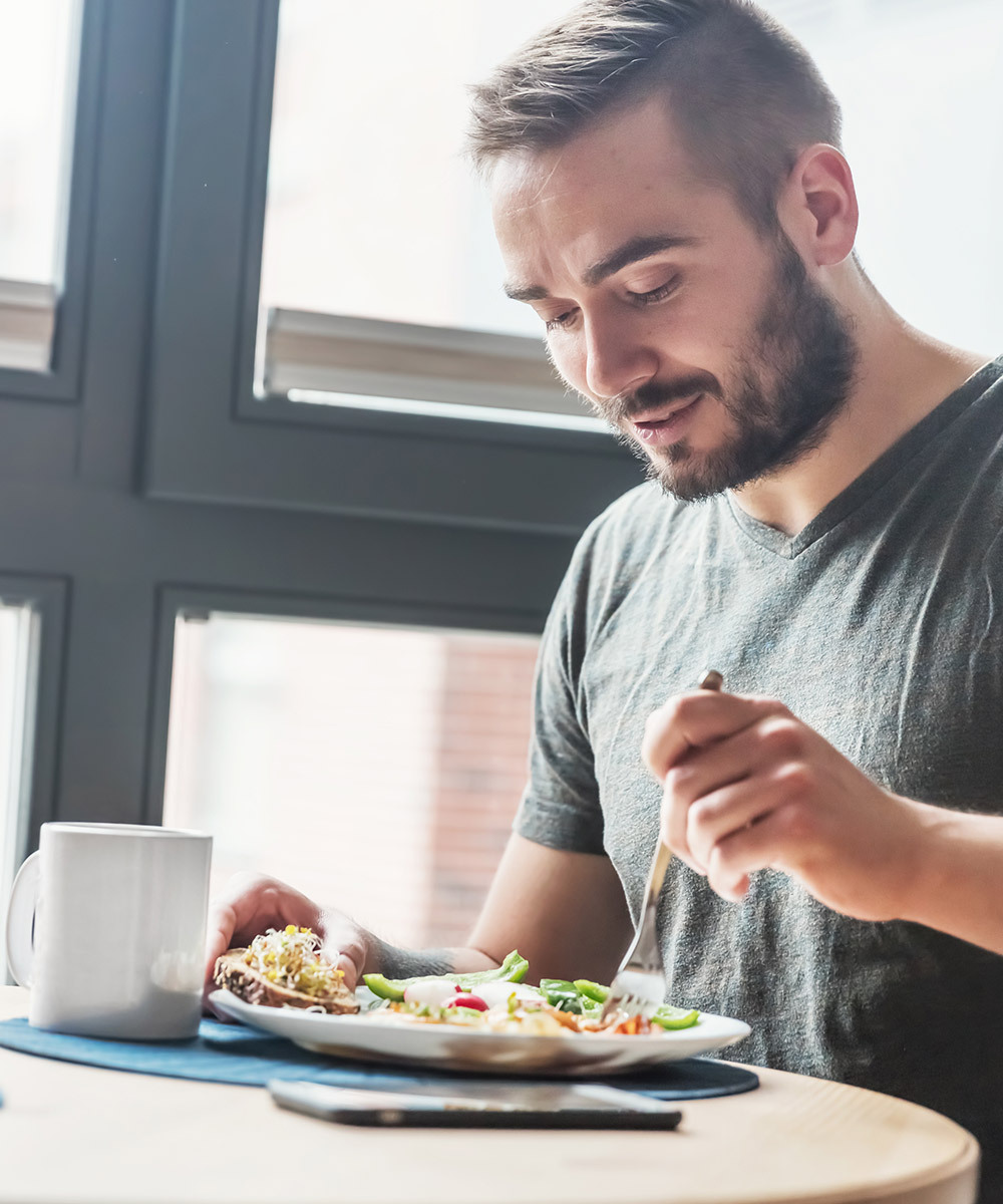 Man eating a heart-healthy breakfast next to a window