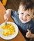 Toddler smiling at camera while eating scrambled eggs
