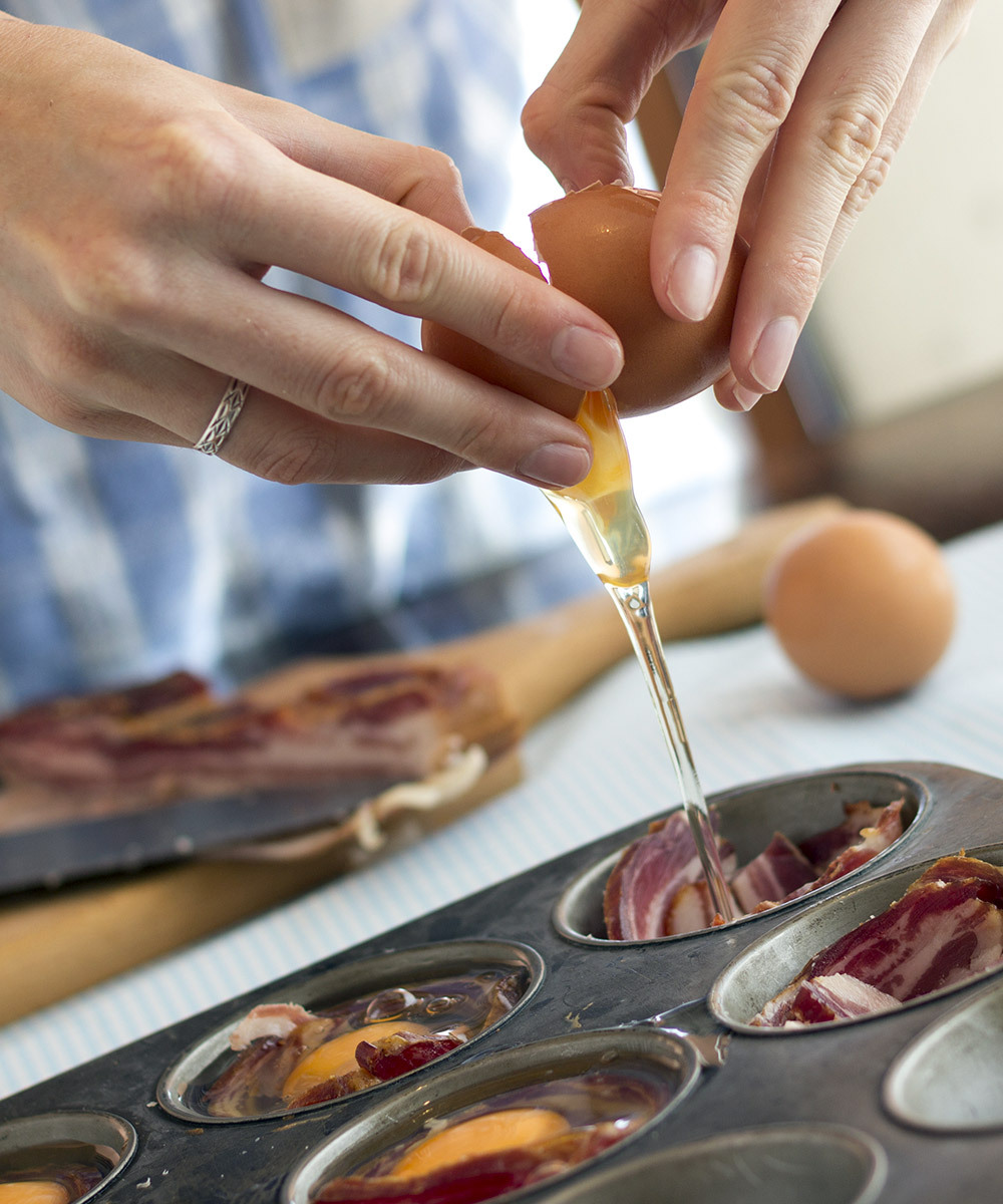Chef cracking an egg into a muffin tray