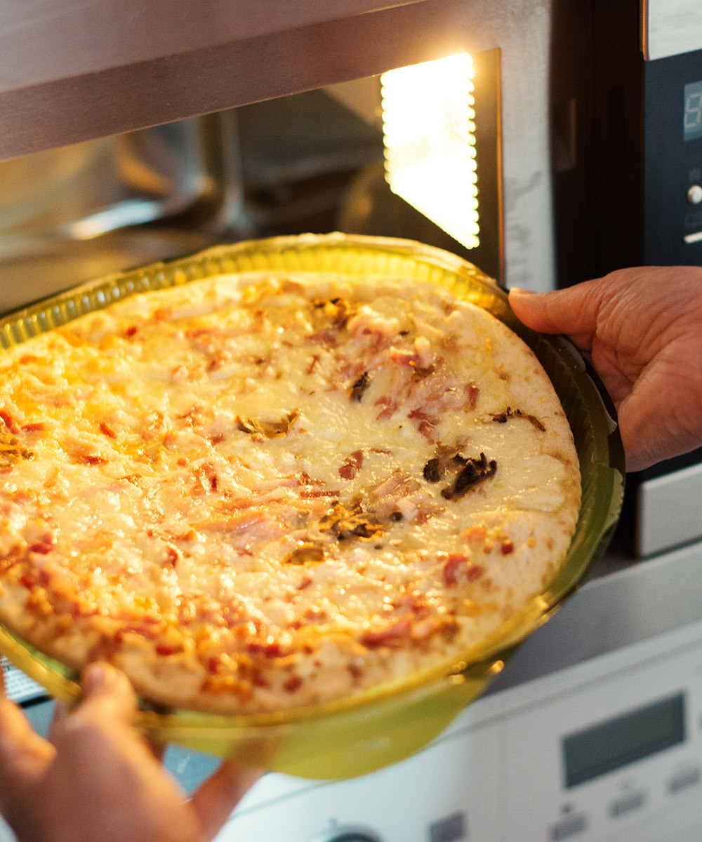 Hands putting flatbread into microwave