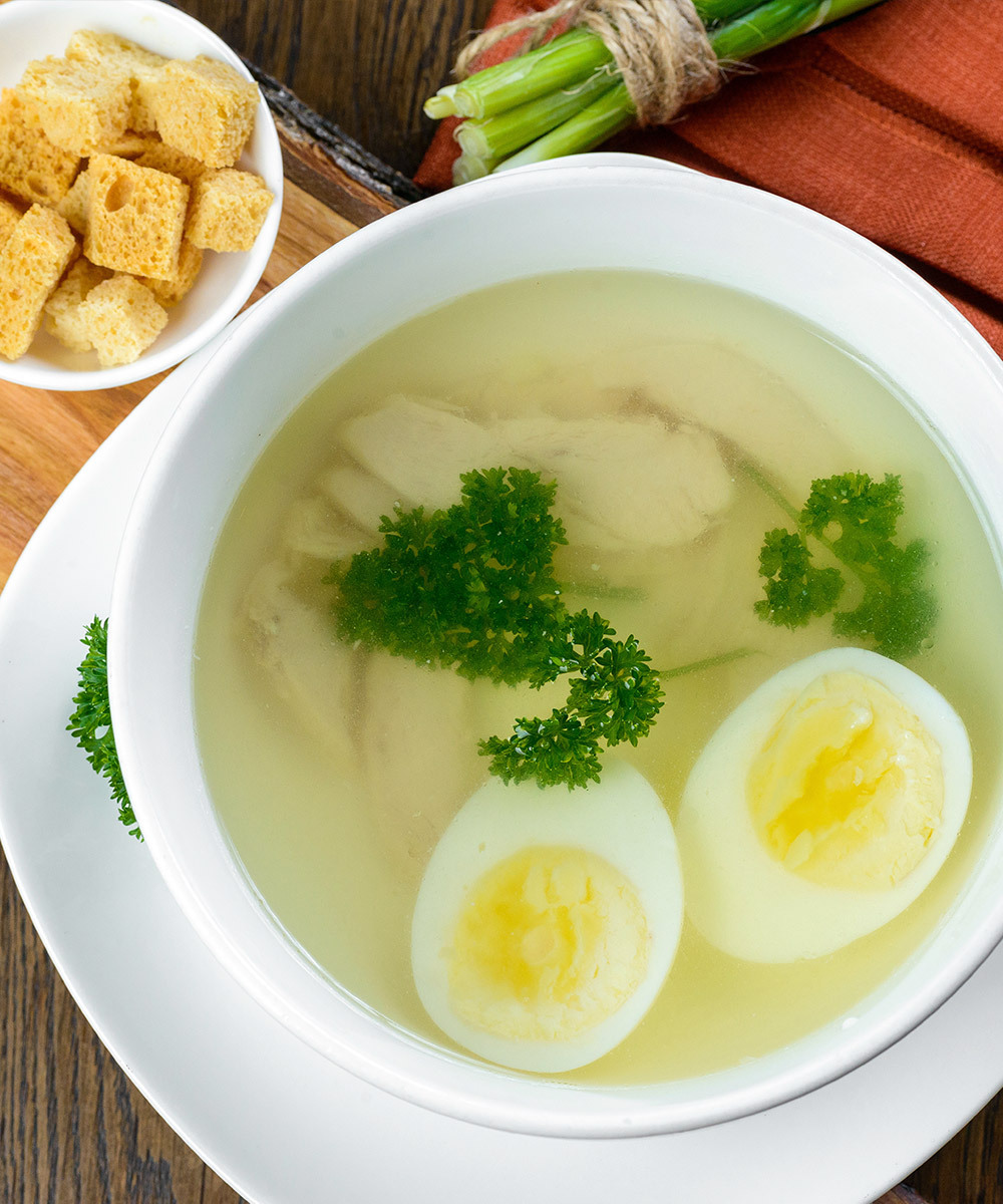 Clear chicken soup with two halves of a hard boiled egg