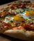 Close up of sunnyside eggs on pepperoni pizza