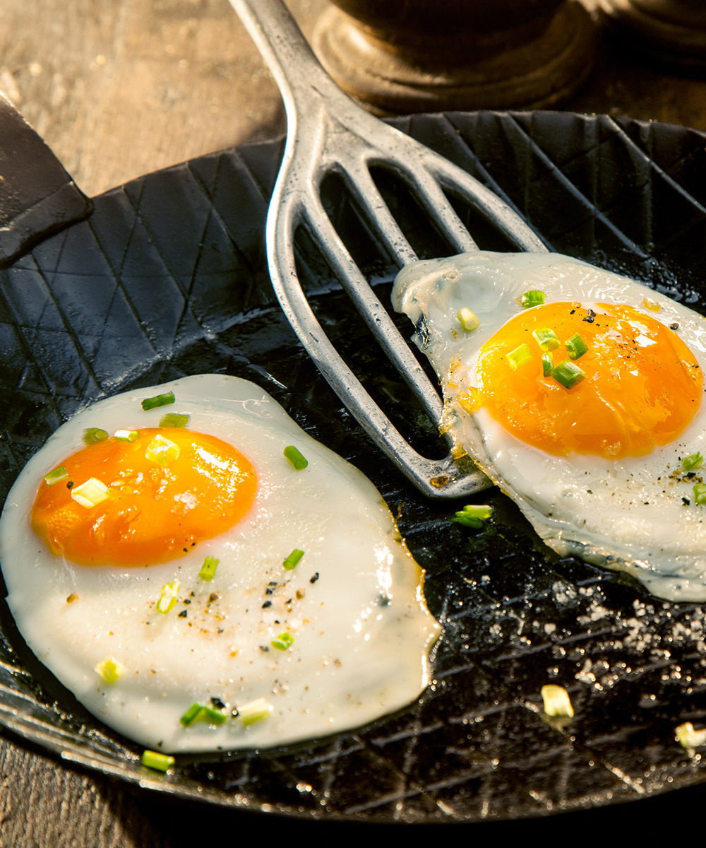 Sunny side eggs getting lifted out of a pan