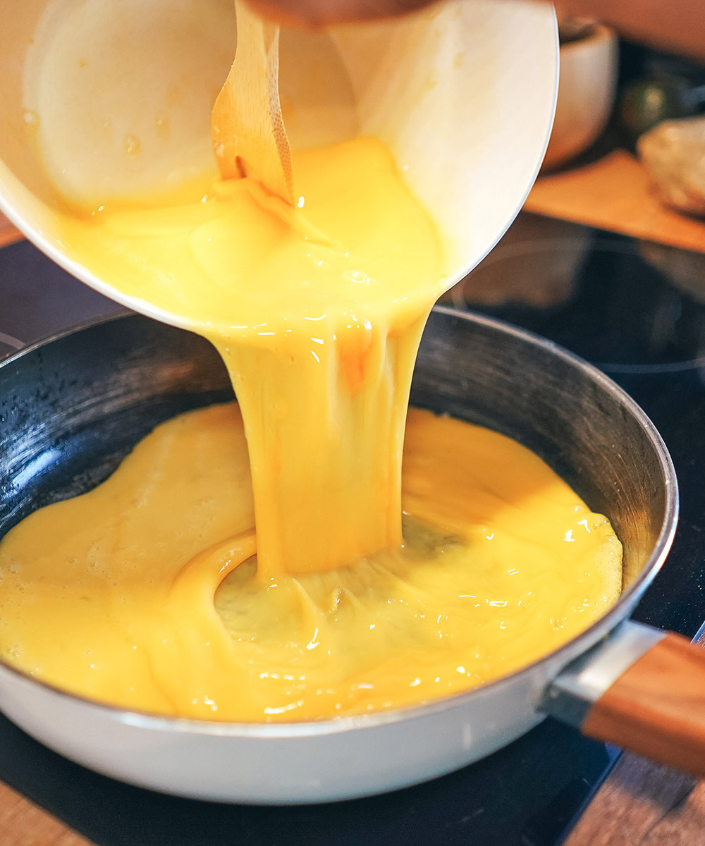 Pouring whisked eggs into a hot pan
